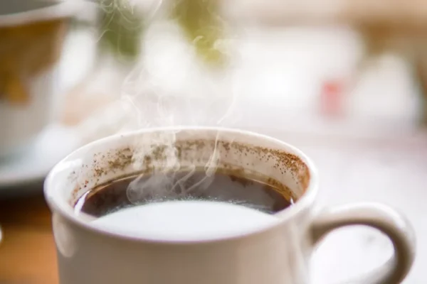 Steaming mug of coffee on a wooden table in warm light