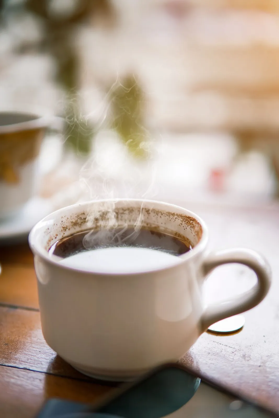 Steaming mug of coffee on a wooden table in warm light