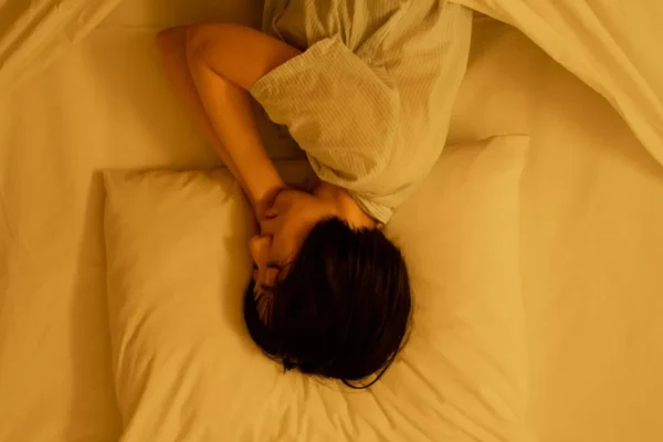 Person curled up asleep under warm yellow bedding