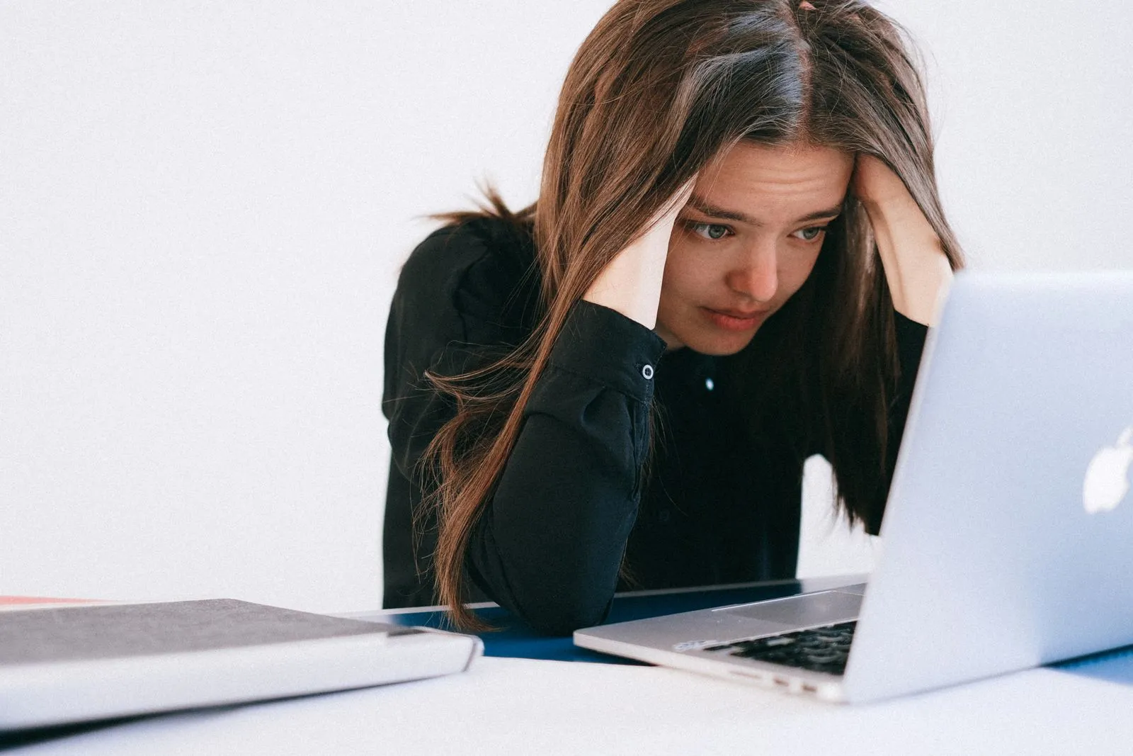 Stressed woman holding her head while working at a laptop